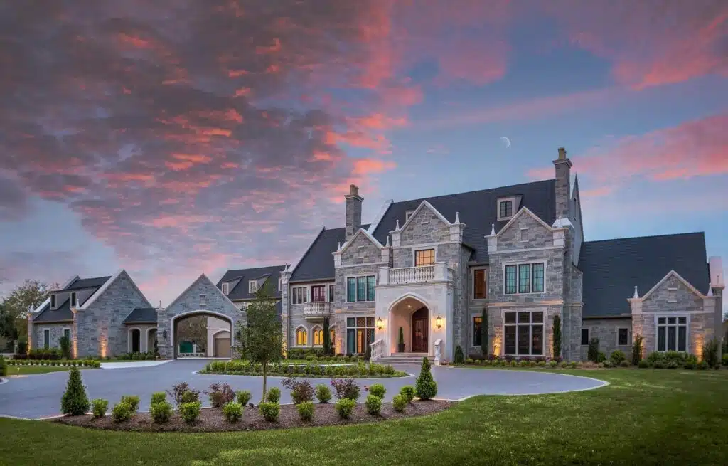 The stone facade and lit entry of a member-built home beneath an evening sky